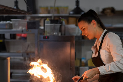 Professional Woman Cooking with Flames in Restaurant Kitchen